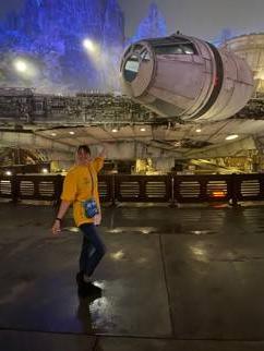 Image of a person in t-shirt and pants standing in front of a spaceship from the Star Wars movies after dark